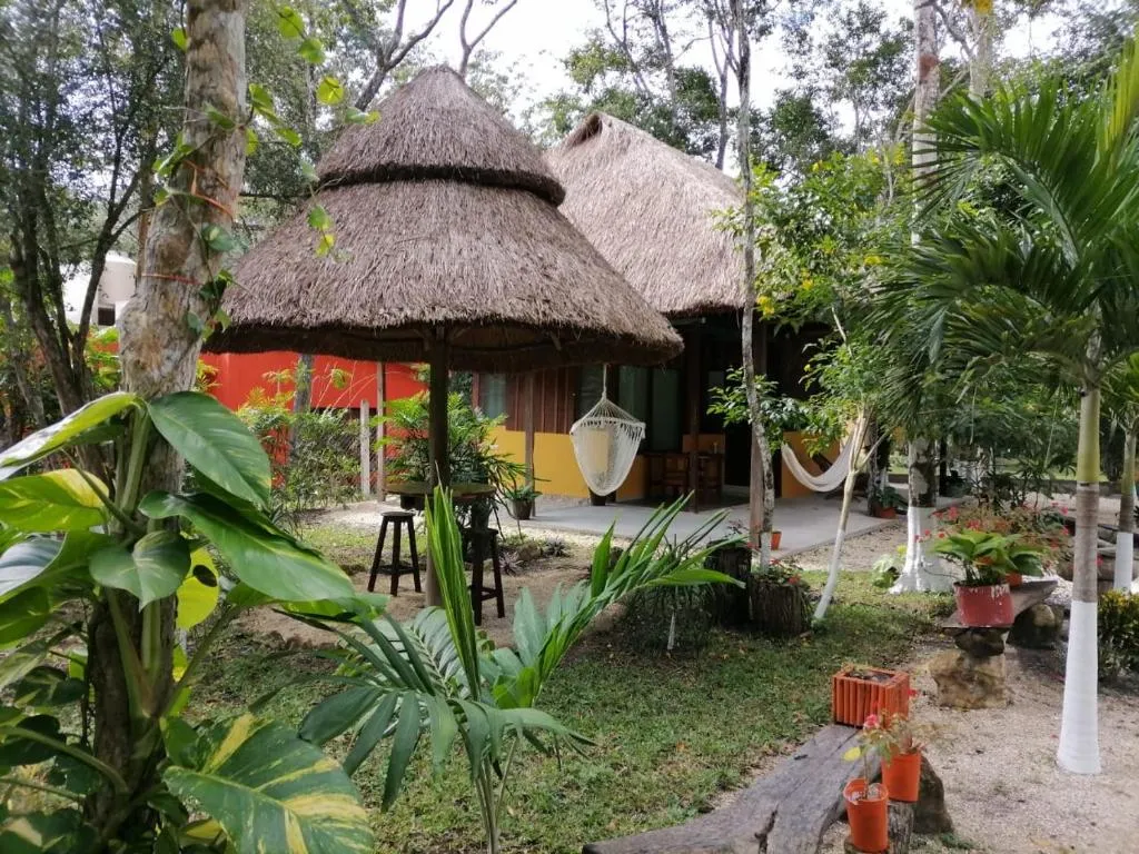Palapas de palma, hamacas y cabañas de colores entre la selva, en el jardín de Casa Las Lolas
