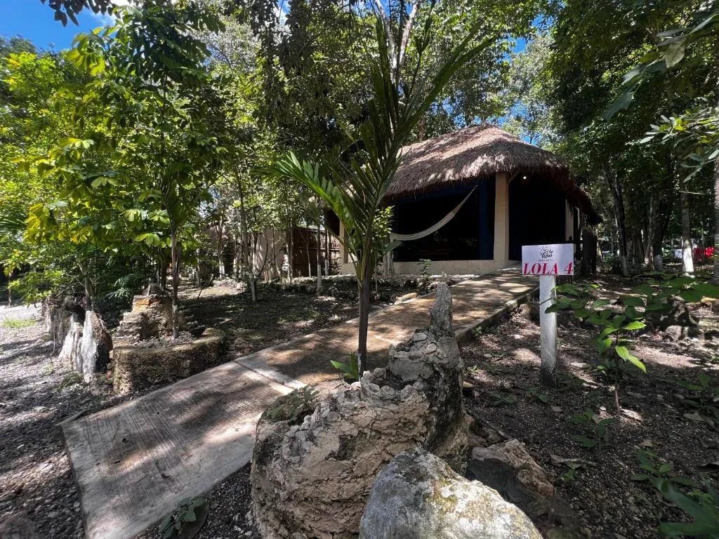 Sendero de piedra entre la selva hacia una cabaña de techo de palapa